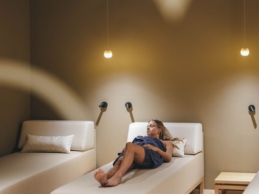 Hotel sull’Alpe di Siusi con spa: Sensoria Dolomites Donna rilassata su lettino in una stanza spa tranquilla con illuminazione soffusa