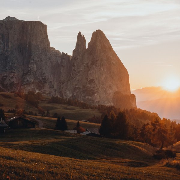 Active holidays in South Tyrol – ready for pure nature? Sunrise over grassy hill with distinctive rock formation in the Dolomites