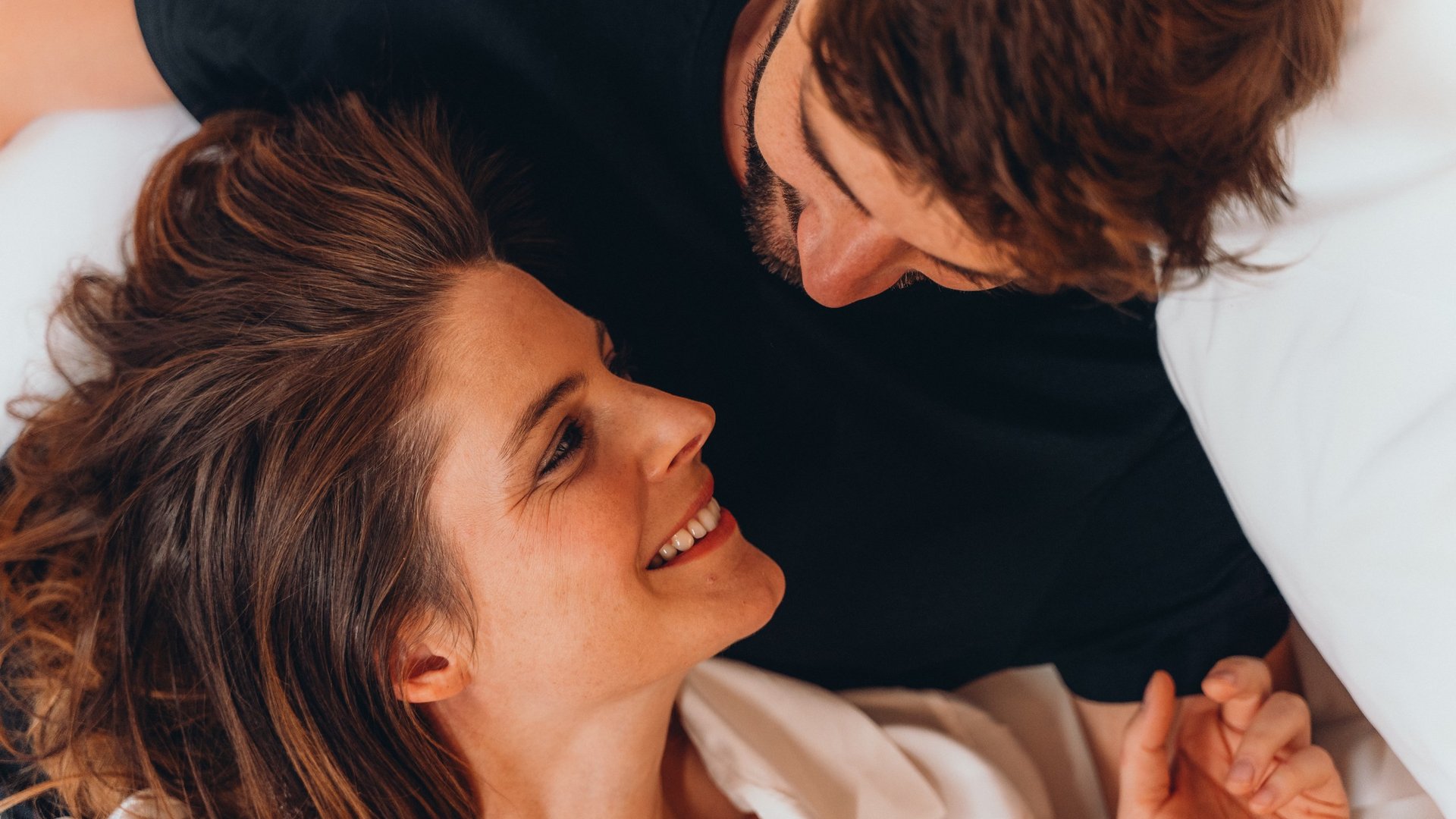 Coppia sdraiata a letto che si guarda con affetto