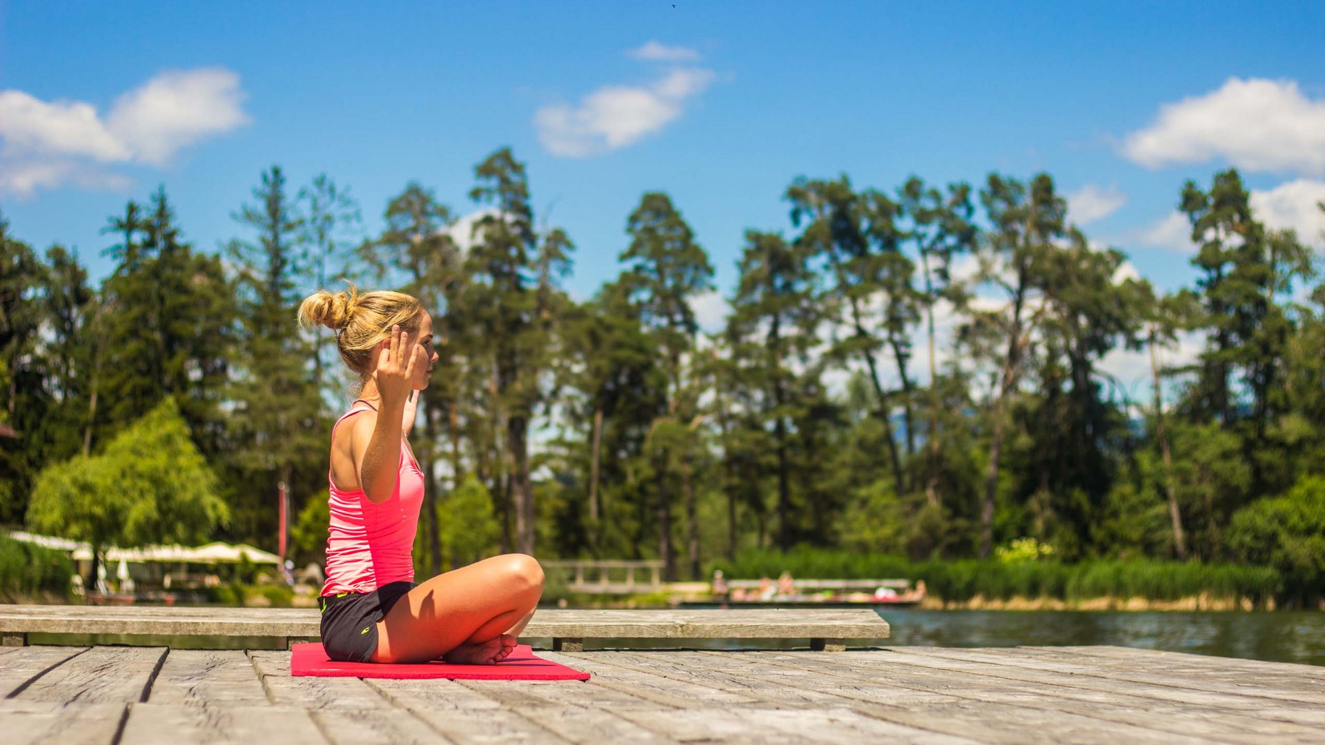 Alpe di Siusi/Seiser Alm Balance – in harmony with nature Woman meditating on red mat by lakeside on sunny day