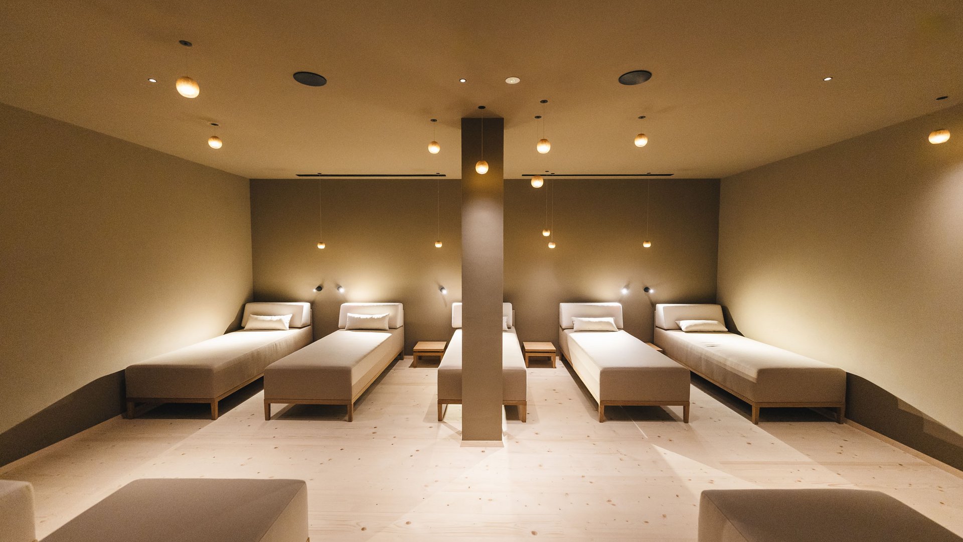 From hiking on Alpe di Siusi/Seiser Alm to the spa area Modern relaxation room with multiple white beds and warm hanging lights