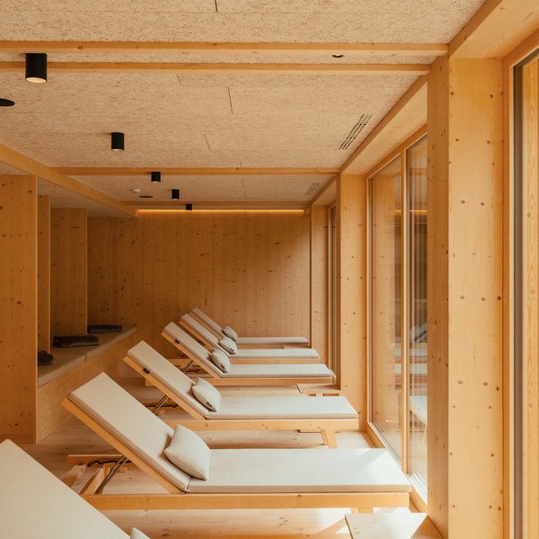 Sensoria Dolomites: Wellnesshotel in den Dolomiten Entspannungsbereich mit Liegestühlen in einem Holzinterieur mit großen Fenstern