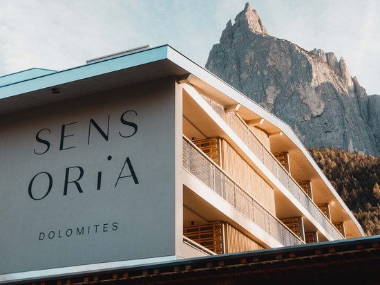 Vacanza di yoga in Trentino-Alto Adige Hotel Sensoria Dolomites davanti a una montagna imponente con cielo blu