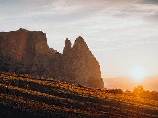 Vacanza all’Alpe di Siusi: Sensoria Dolomites Tramonto arancione sulle montagne e su un prato