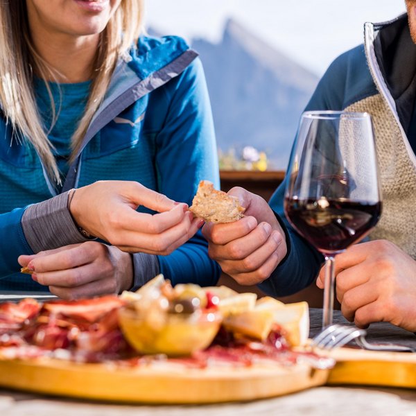 Settimana bianca sulle Dolomiti, al Sensoria Dolomites Coppia che mangia pane e antipasti con vino all'aperto