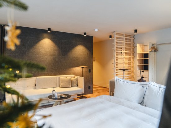 Sensoria Dolomites – Urlaub in Seis am Schlern Moderne Hotelzimmer mit Bett, Sofa und weihnachtlich geschmücktem Baum
