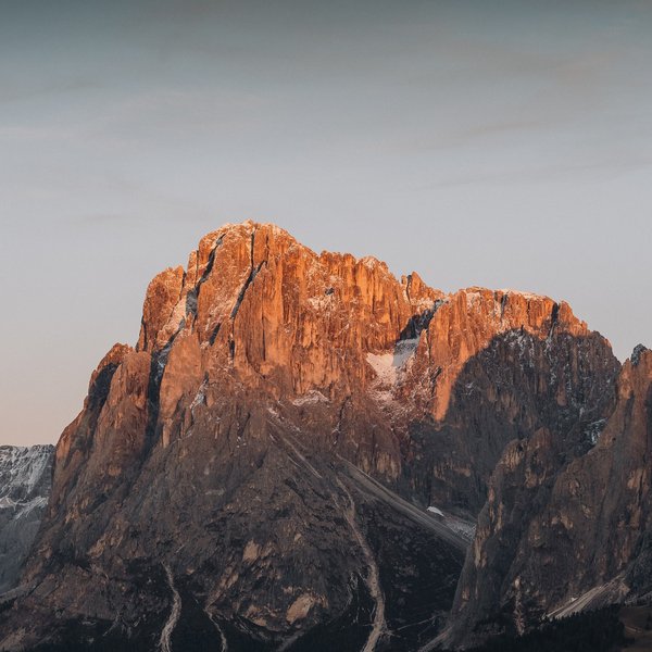 Active holidays in South Tyrol – ready for pure nature? Mountain peaks lit by warm sunset light with light snow cover