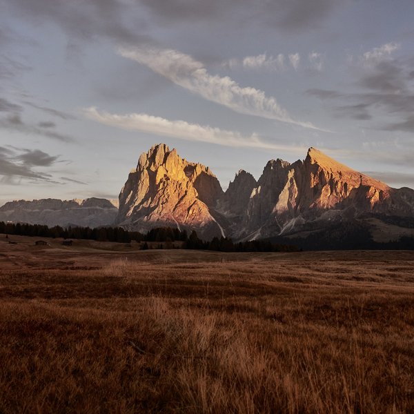 Meteo all’Alpe di Siusi? Soleggiato! Paesaggio montano all'alba con cime illuminate e ampia valle