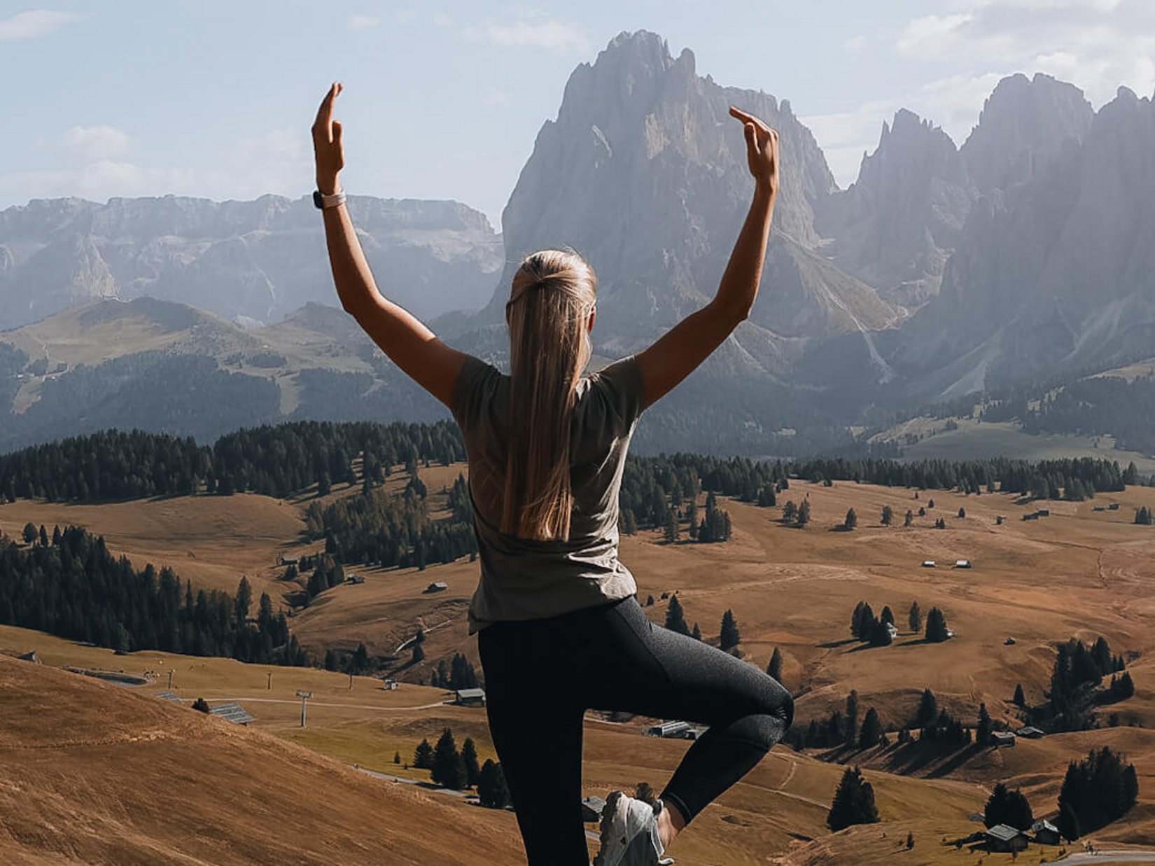 Offers – holidays in the Dolomites UNESCO World Heritage Woman doing yoga in the mountains with view of valley and clear sky