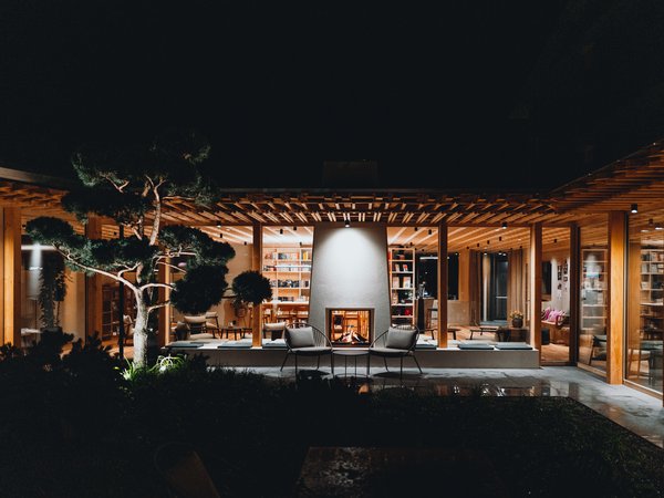 Wellness Aphrodite: Sensoria Dolomites among the winners Modern wooden house with lit fireplace and garden at night