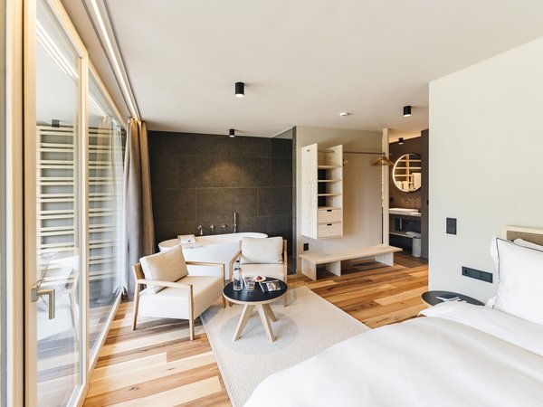Wellness Aphrodite: Sensoria Dolomites among the winners Modern hotel room with bed, seating area, bathtub, and wooden floor