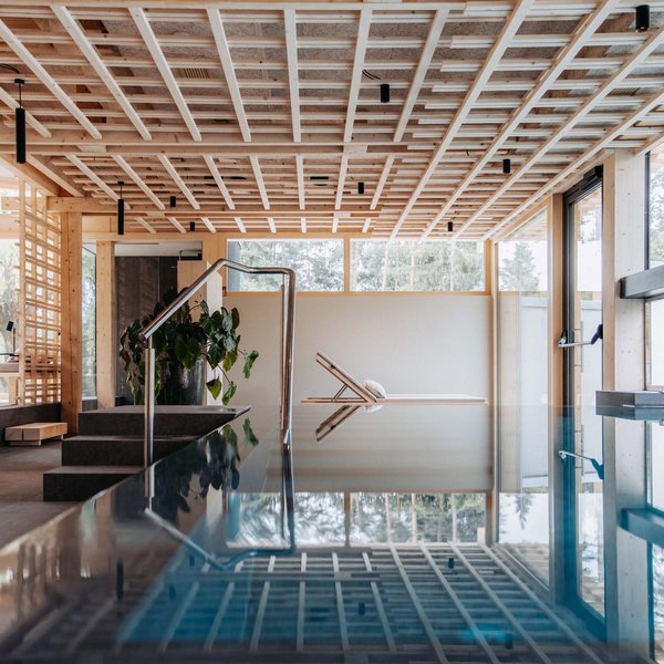 Hotel in mezzo alla natura: area spa del Sensoria Dolomites Area benessere moderna e tranquilla con piscina e lettino vicino a grandi finestre