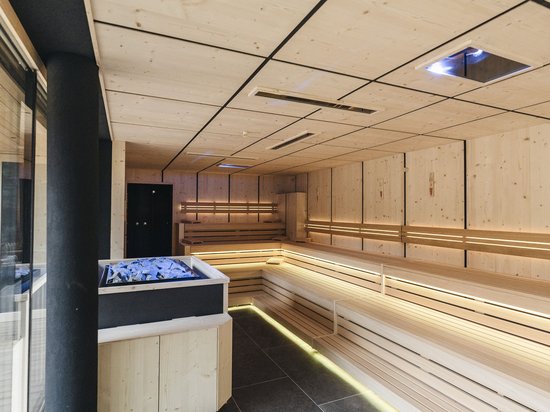 A day spa in the Dolomites to soothe your soul Modern bright sauna with wooden benches and stone heater