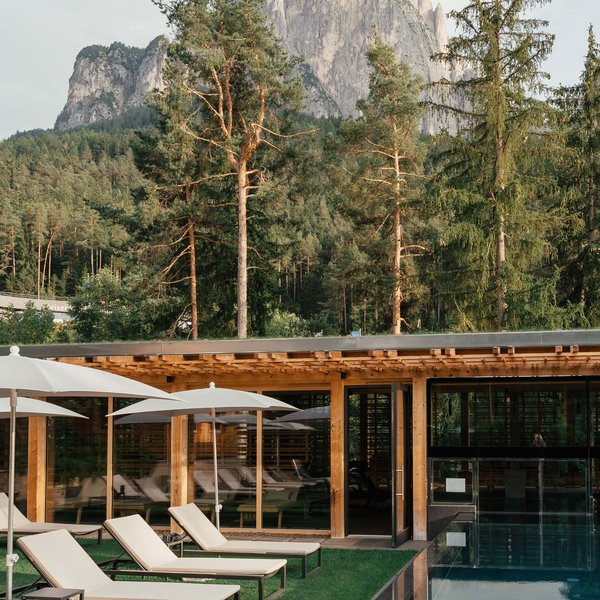 Sensoria Dolomites: Wellnesshotel in den Dolomiten Poolbereich mit Liegestühlen und Bergblick in einem Waldhotel