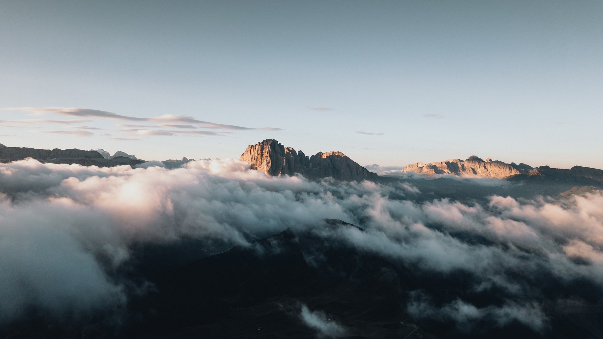 Holidays in the Dolomites – holidays at Sensoria Dolomites Mountain peaks rising above fog under clear sky at sunrise
