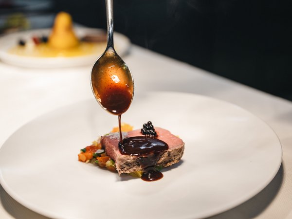 Wellness Aphrodite: Sensoria Dolomites among the winners Sauce poured over a slice of pink cooked meat on a white plate