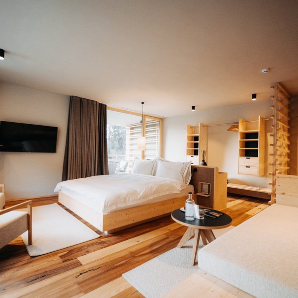 Sensoria: Private Spa Suite mit Whirlpool in Südtirol Modernes Hotelzimmer mit Holzmöbeln und gemütlichem Bett.