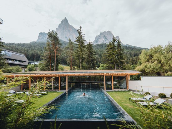 Sensoria Dolomites: hotel in montagna Donna che nuota in piscina all'aperto con montagne e alberi sullo sfondo