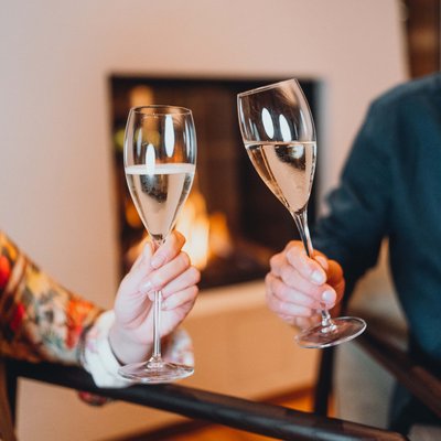 Essence single room North Two people clinking champagne glasses by the fireplace