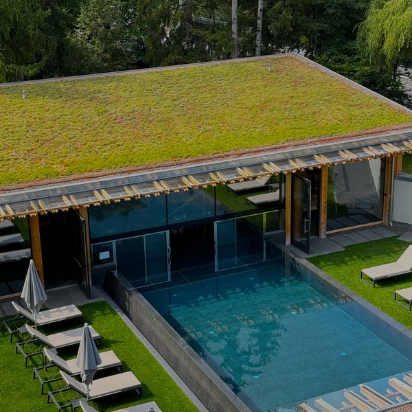 From hiking on Alpe di Siusi/Seiser Alm to the spa area Modern pool with green roof and sun loungers next to a forest