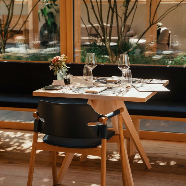 Sensoria Dolomites: Wellnesshotel in den Dolomiten Elegant gedeckter Tisch mit Gläsern und Blumen in hellem Restaurant