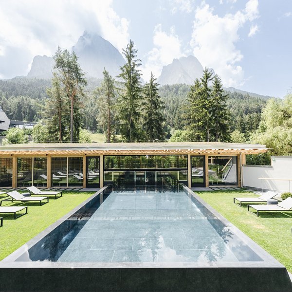 Sensoria Dolomites: Wellnesshotel in den Dolomiten Moderner Pool mit Liegestühlen und Bergblick an einem sonnigen Tag