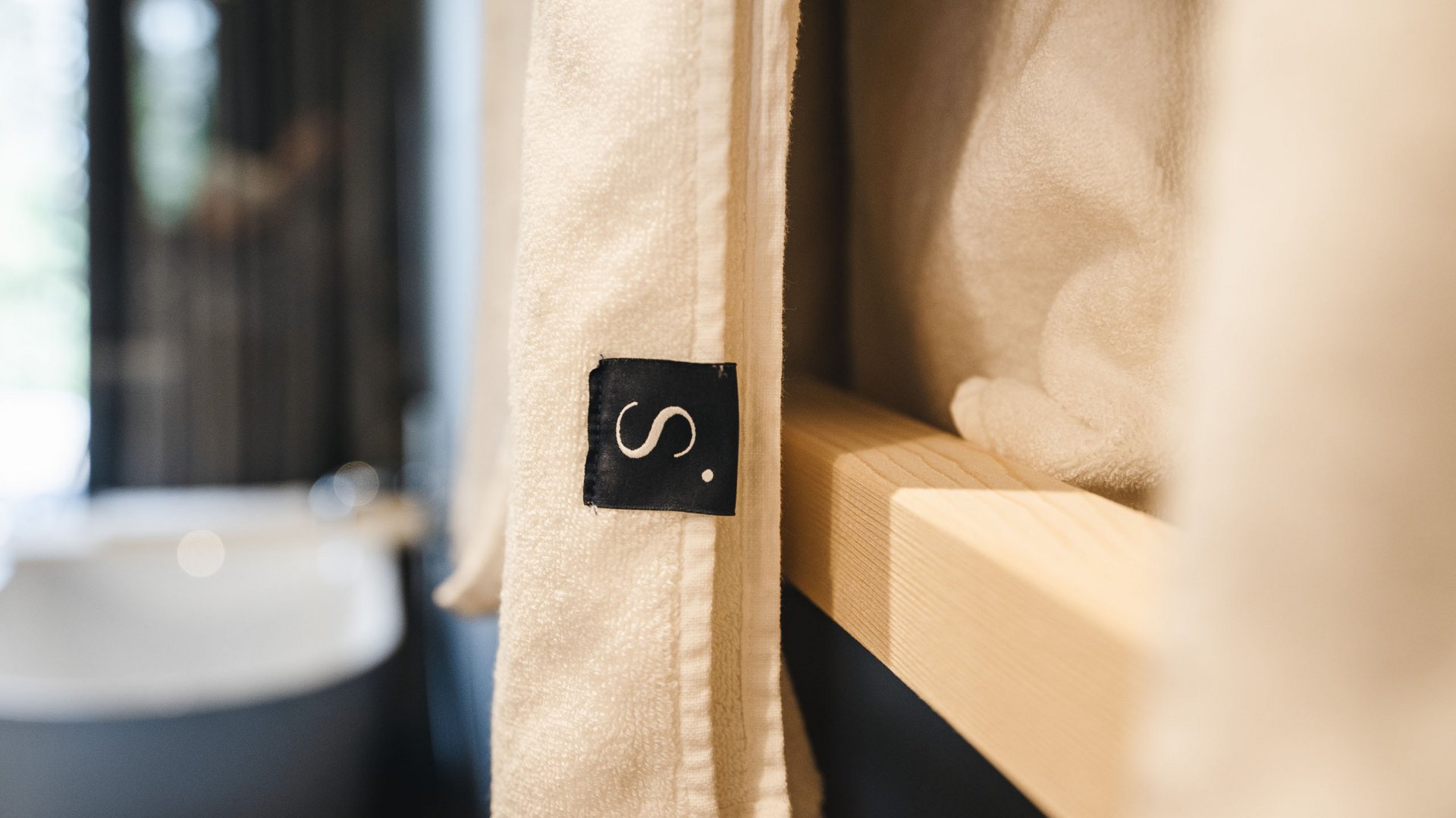 Sustainability at Sensoria Dolomites White towel with black label on wooden shelf in bathroom