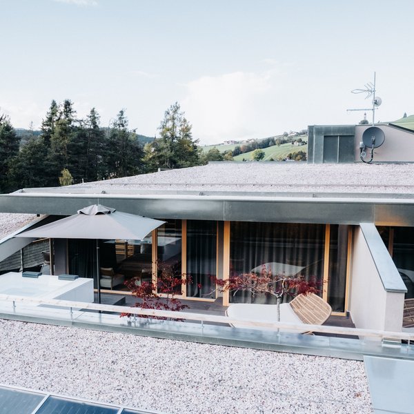 Sensoria: Private Spa Suite mit Whirlpool in Südtirol Moderner Balkon mit Sonnenschirm, Pflanzen und alpiner Landschaft im Hintergrund
