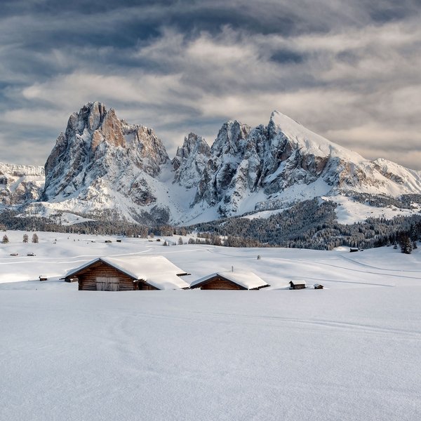 Settimana bianca sulle Dolomiti, al Sensoria Dolomites Baite innevate davanti a montagne frastagliate sotto un cielo nuvoloso