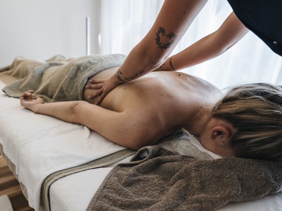 Kostbare Augenblicke in Ihrem Romantikhotel in den Dolomiten Frau erhält Rückenmassage in einem Wellnessraum