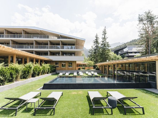 Vacanza di yoga in Trentino-Alto Adige Area piscina moderna con lettini davanti a un hotel con alberi sullo sfondo