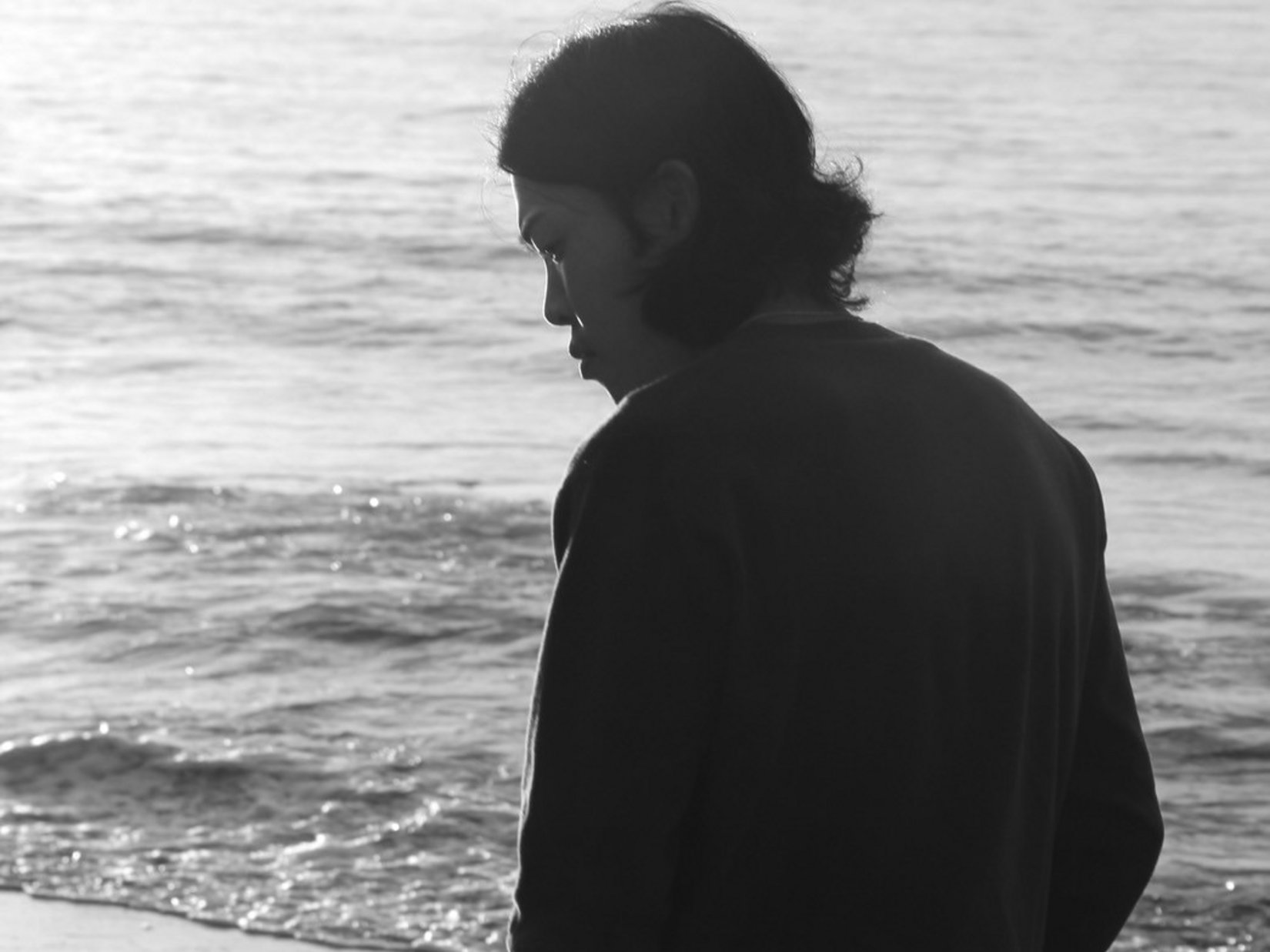 Sensoria Art Edition Person am Strand blickt nachdenklich aufs Wasser bei Sonnenuntergang