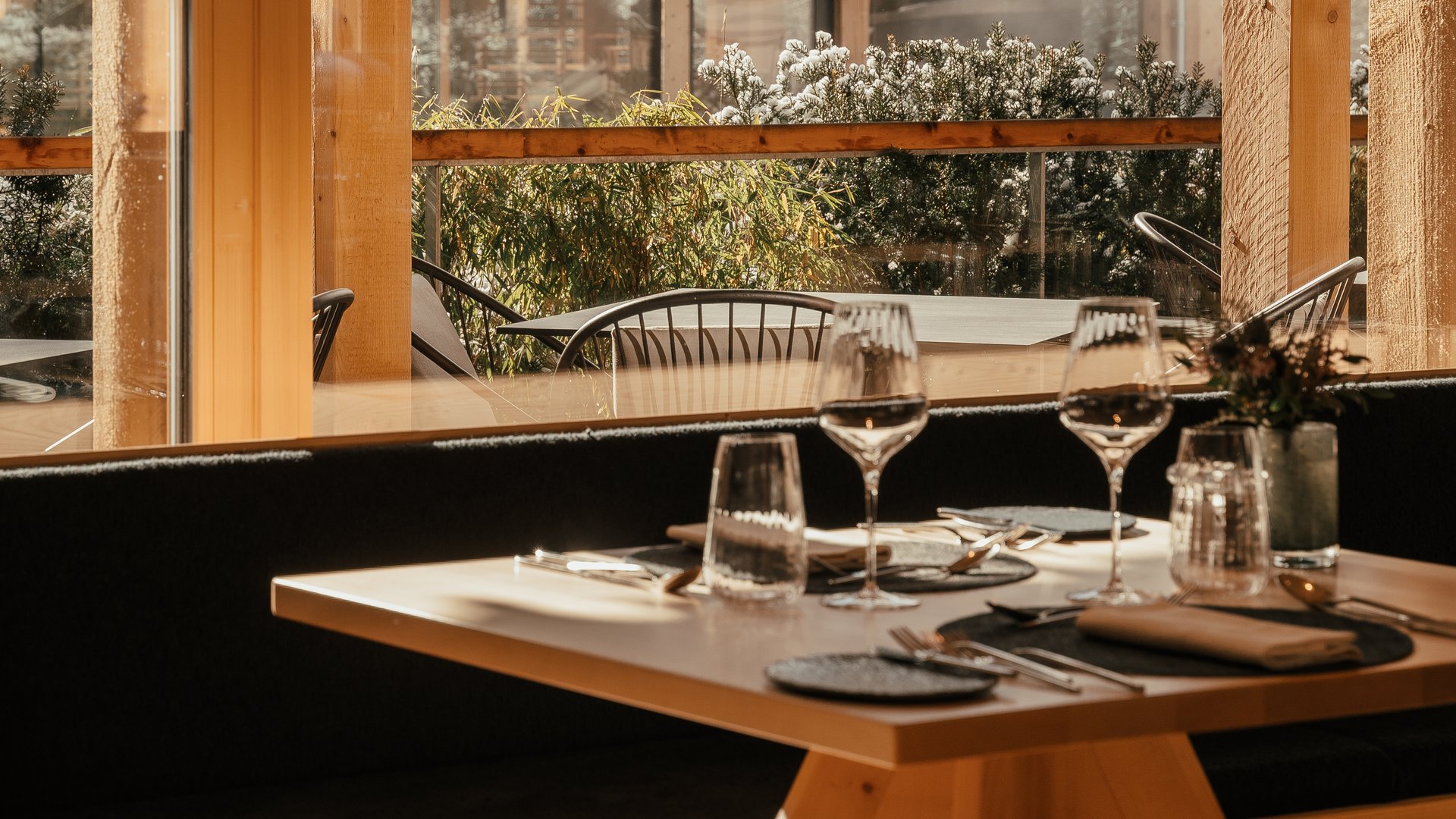 Südtiroler Rezepte. Neu interpretiert. Ein gedeckter Tisch in einem Holzrestaurant mit verschneitem Wald im Hintergrund