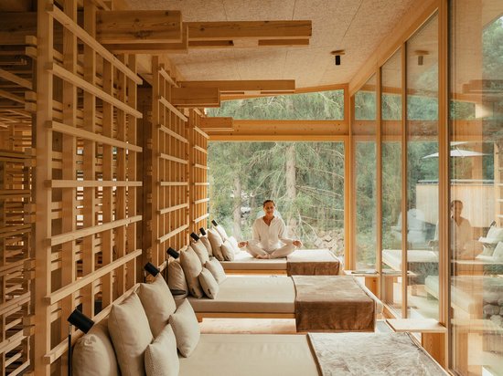 Vacanza di yoga in Trentino-Alto Adige Persona medita in stanza moderna di legno con letti e ampie finestre