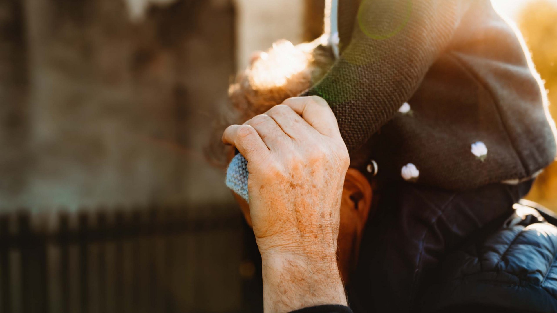 Places of spiritual power, favourite rooms, hosts with heart Older man carrying child on shoulders in sunlight