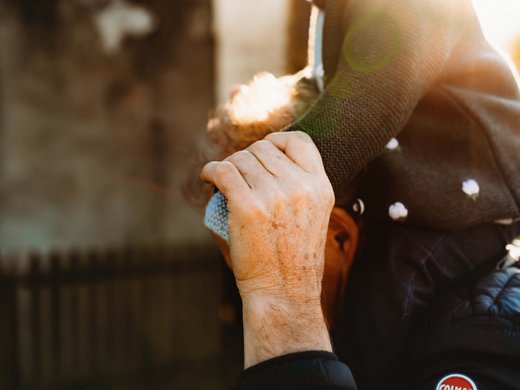 Sustainability at Sensoria Dolomites Older man carrying child on shoulders in sunlight