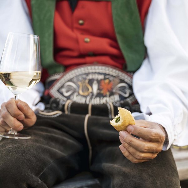 Sensoria Dolomites: much more than a hotel in South Tyrol Person in traditional attire holding white wine glass and stuffed dough piece