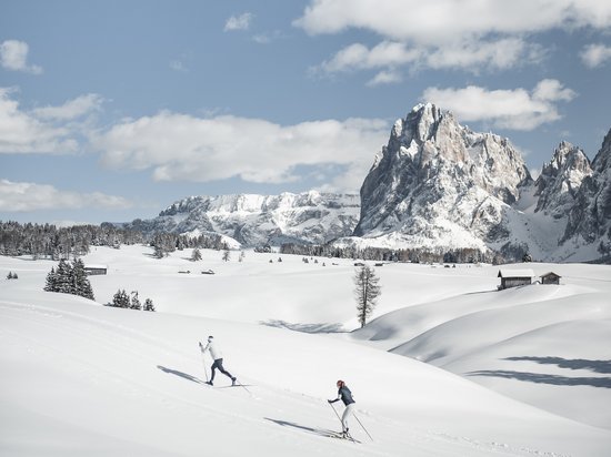 Settimana bianca sulle Dolomiti, al Sensoria Dolomites Due sciatori su paesaggio innevato con cielo azzurro e montagne