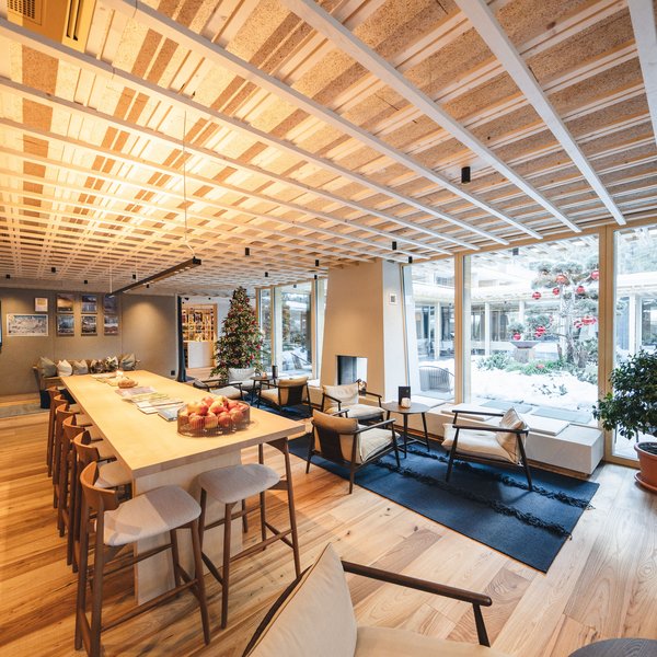 Sensoria Dolomites: il vostro hotel sull’Alpe di Siusi Soggiorno moderno con albero di Natale e grande tavolo in legno