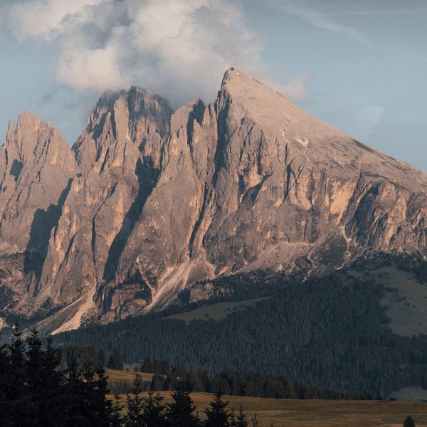 Sustainability at Sensoria Dolomites Rocky mountain peaks lit by sunset with clouds in the sky
