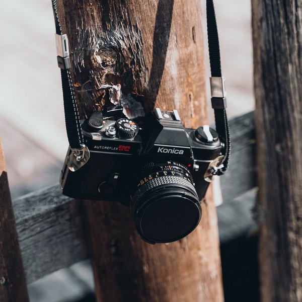 Active holidays in South Tyrol – ready for pure nature? Black vintage camera hanging on a wooden post