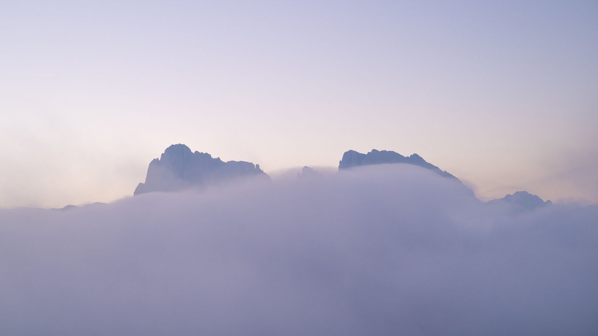 Ein Helikopterflug in den Dolomiten – Augenblicke über den Gipfeln Berggipfel, die aus dichter Wolkendecke bei Sonnenaufgang ragen