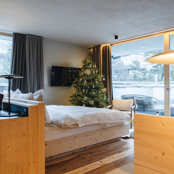 Sensoria Dolomites: il vostro hotel sull’Alpe di Siusi Camera d'albergo accogliente con albero di Natale e ampia finestra con vista sulle montagne