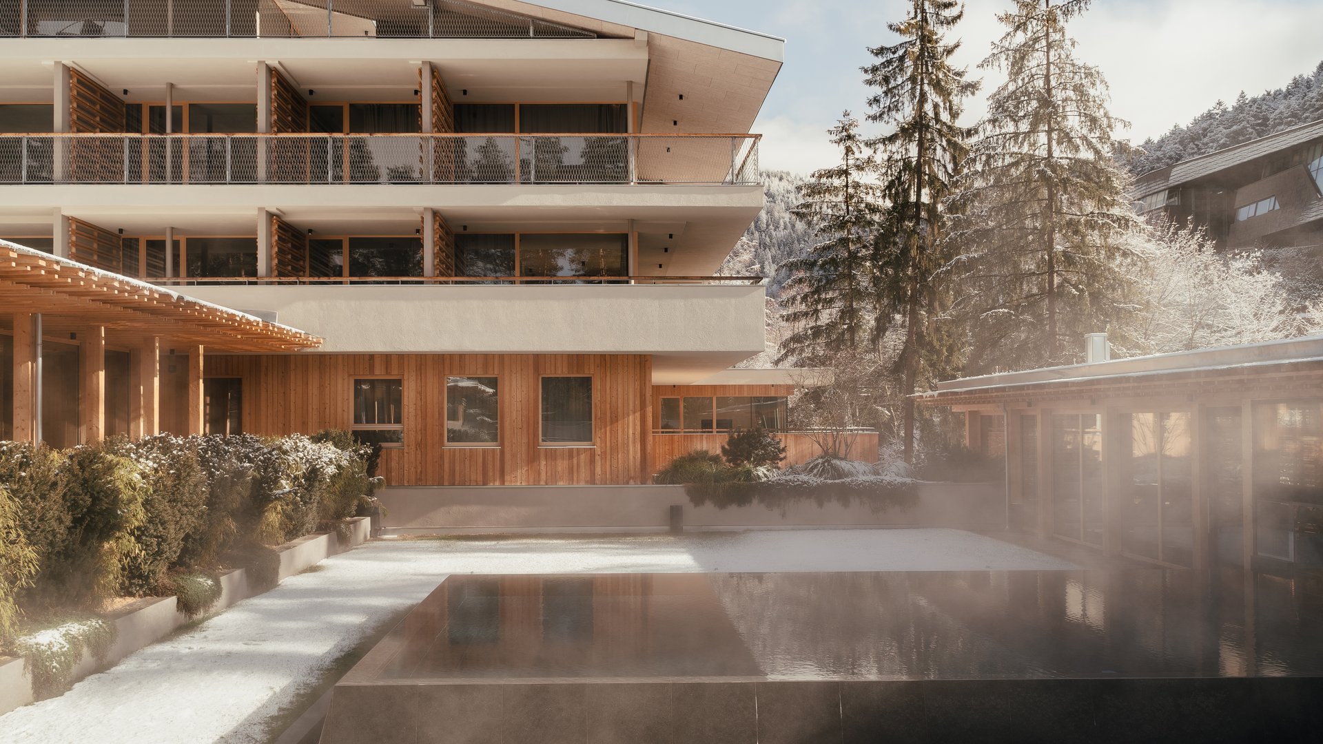 Sensoria Dolomites – Urlaub in Seis am Schlern Modernes Gebäude mit beheiztem Außenpool und verschneiter Landschaft