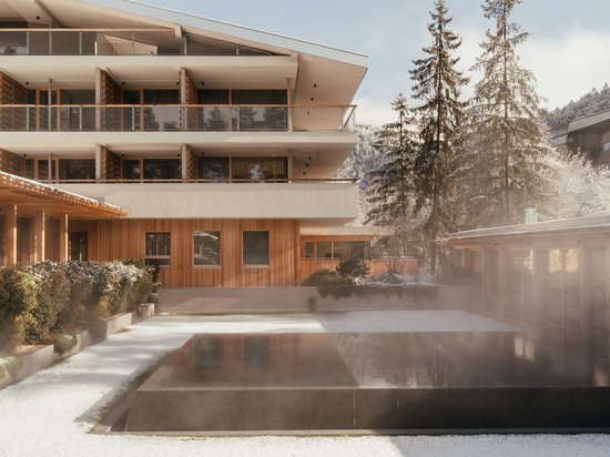 Sensoria Dolomites: your hotel in the Italian Alps Modern building with heated outdoor pool and snowy surroundings