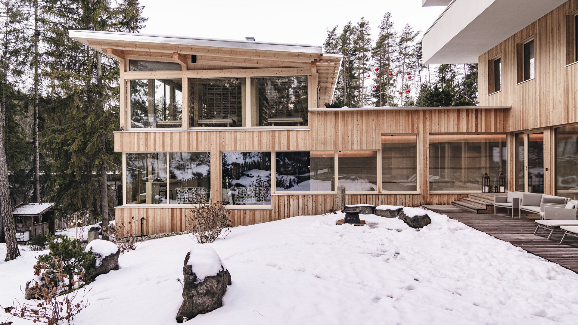 Hotel in mezzo alla natura: area spa del Sensoria Dolomites Casa moderna in legno invernale con giardino innevato e alberi di pino circostanti